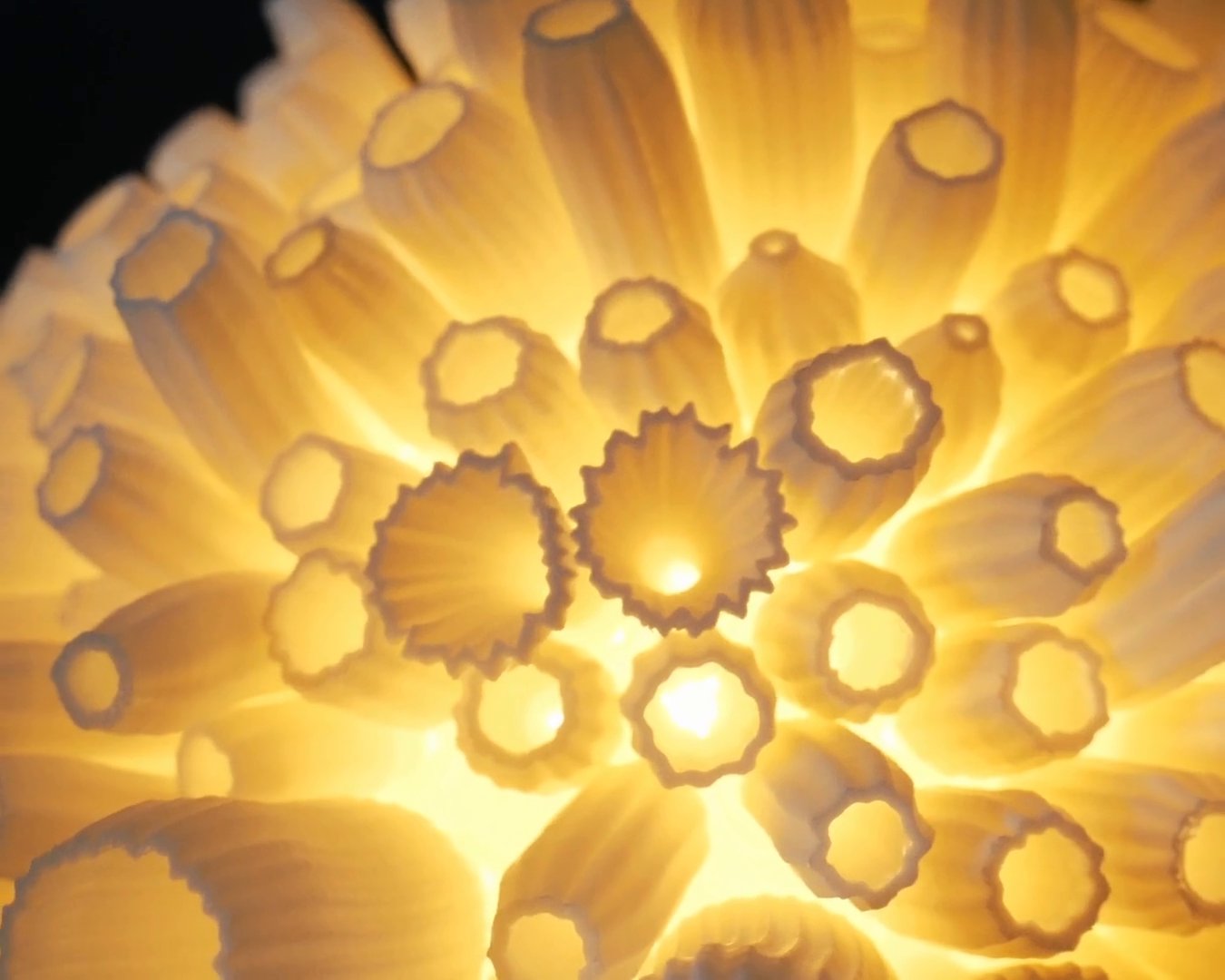 Close-up of the lit Bloom lamp: rows of fluted petals with the warm light shining through their walls.