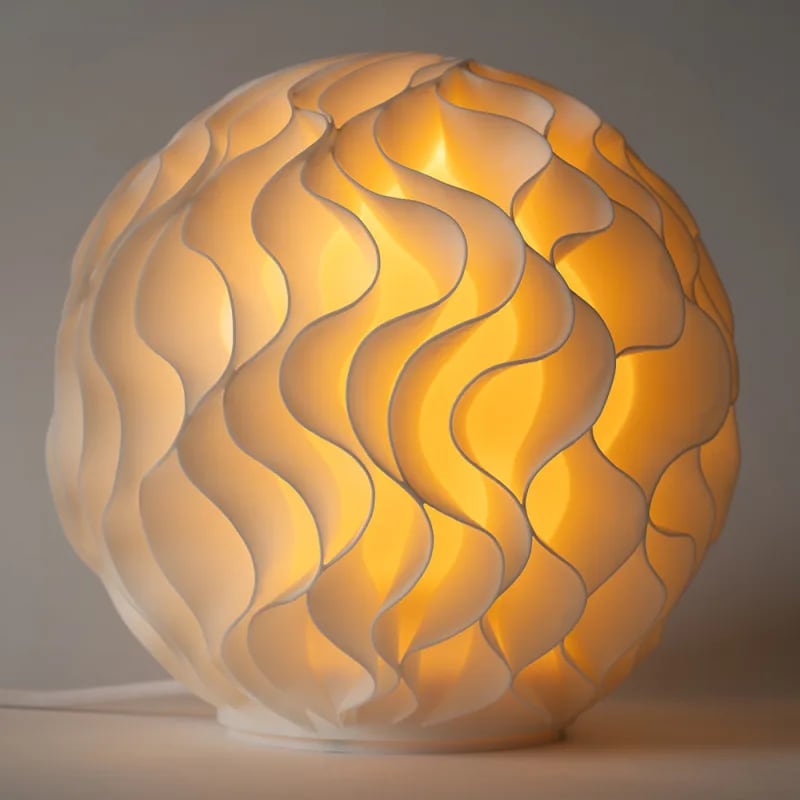 Close view of a lit Growth lamp: rows of thin white fins in waves, with warm light between them.